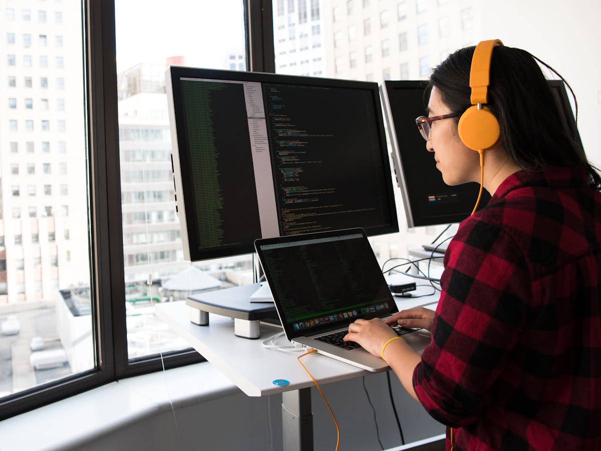 Developer at desk with code on monitors